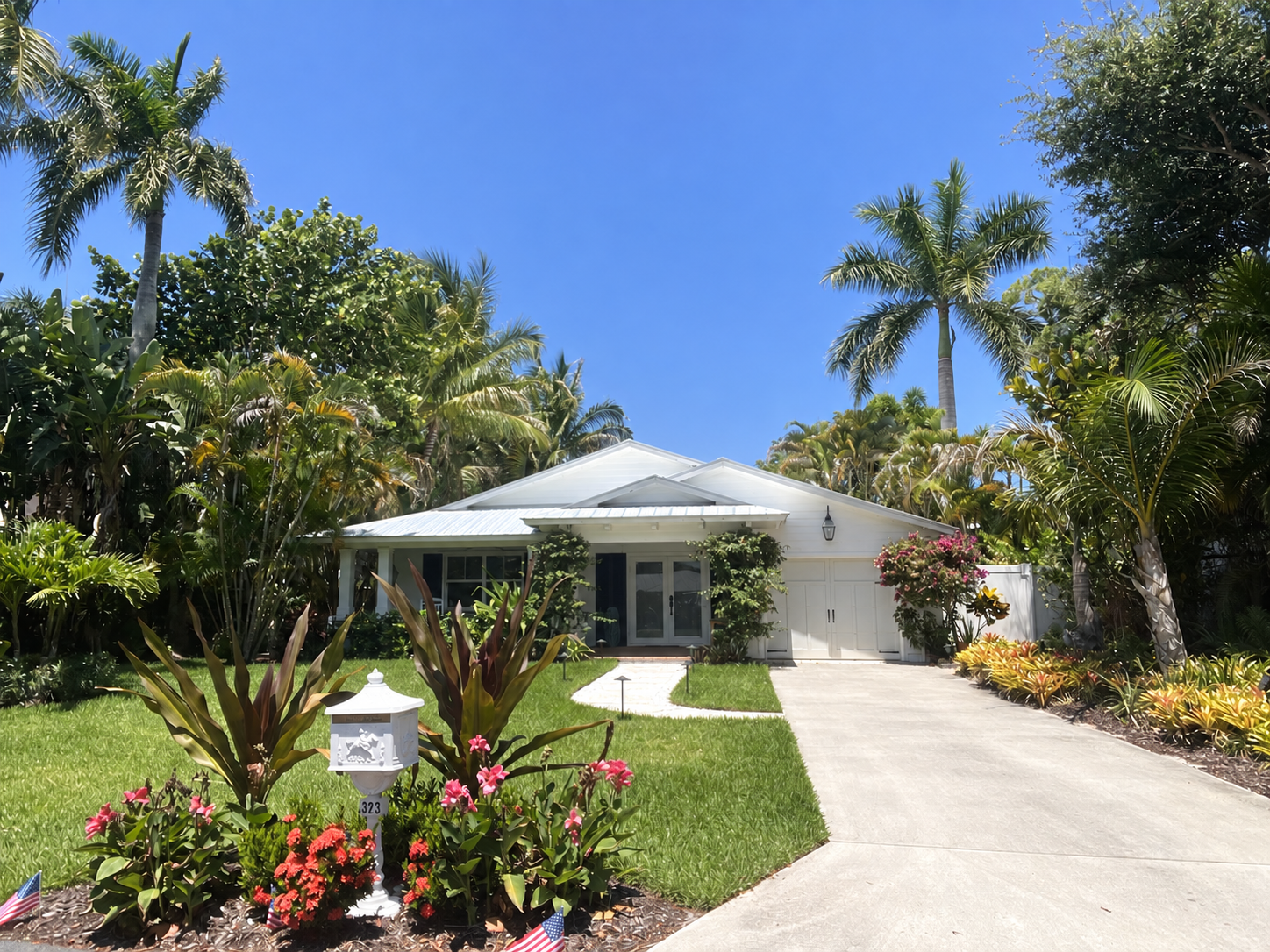 White coastal cottage surrounded by palms and tropical landscaping